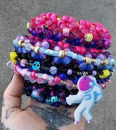 a hand holding a stack of bracelets with an astronaut charm attached to one of them