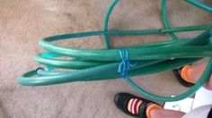 a person standing next to a green hose on top of a carpeted floor with their feet in the air