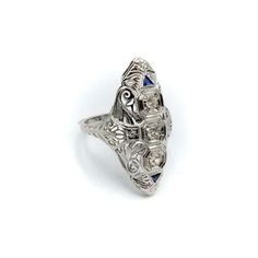 This is part of Chairish’s Fine Jewelry assortment.  This is a stunning Art Deco navette-shaped 18 karat white gold, diamond and sapphire ring. The ring has some excellent filigree work that merges organic abstract shaped with sharp angular lines.   The centre diamond measures 3.35 mm, and the diamonds flanking the centre diamond are 3 mm each, for a total carat weight of approximately .5 carat. The diamonds are three Old European Cuts with high tables. The diamonds are set in octagon shapes. Ab High Tables, Diamond And Sapphire Ring, Organic Abstract, Ring Size 7, Abstract Shapes, White Gold Diamonds, Sapphire Ring, Gold Diamond, Sapphire