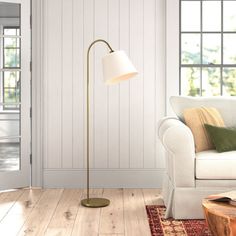 a living room with white walls and wood flooring, a large lamp in the corner