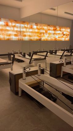 an empty room with mirrors and benches in front of a large glass wall that is reflecting the sky