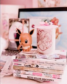 a stack of books sitting on top of a desk next to a laptop computer and toy