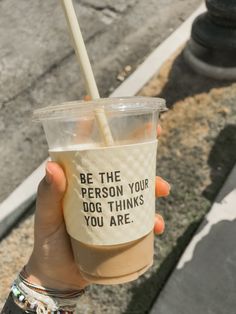 a person holding up a cup with a straw in it that says be the person you dog thinks you are