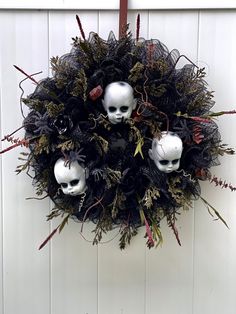 a wreath with two skulls hanging from it's side and some plants in the middle