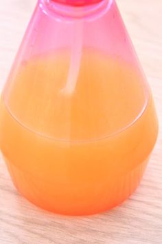 an orange and pink vase sitting on top of a wooden table