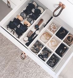 an open drawer filled with lots of glasses and other items on top of carpeted floor