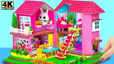 a pink doll house with a cat on the roof and stairs to it's second floor