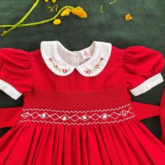 Christmas Red Hand-Smocked Baby Girl Dress This adorable hand-smocked baby girl dress is perfect for the festive season or any special occasion! The vibrant red color and intricate smocking make it a standout piece that combines timeless charm with comfort. Features: Color: Solid vibrant red, perfect for the holiday season or special events. Hand Smocking: Beautifully detailed hand-smocked bodice with white and red embroidery, adding a classic and elegant touch. Collar Design: White Peter Pan co Red Smocked Dresses, Red Cotton Dress With Smocked Back, Red Cotton Dress With Smocked Cuffs, Smocked Christmas Dress, Rouge Uni, Smocked Christmas Dresses Baby, Birthday Frocks, Back To School Dress, Smocked Baby Girl Dresses