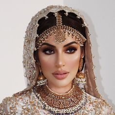 a woman in a bridal gown with jewelry on her head and veil over her face