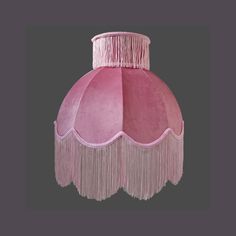 a pink lamp shade with fringes hanging from it