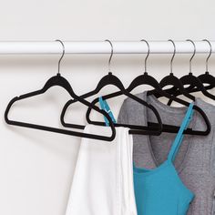 three shirts hanging on a clothes rack in front of a white wall with black hangers