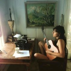 a woman sitting at a desk with a guitar