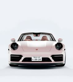 the front view of a pink porsche sports car with two people in it's passenger seat