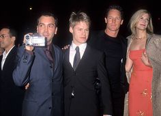 three men and one woman posing for a photo with a camera in front of them