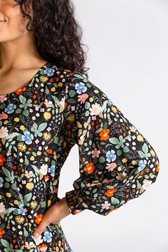 a woman with curly hair wearing a black floral dress