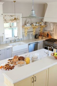 a kitchen filled with lots of counter space and white cabinets next to a stove top oven