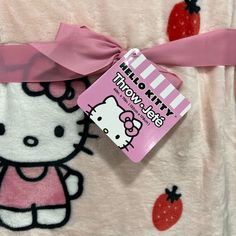 a hello kitty blanket with a pink bow on it's side and a tag attached to the back