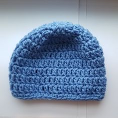 a blue crocheted hat sitting on top of a white table next to a wall