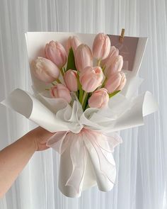 a hand holding a bouquet of pink tulips