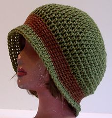 a mannequin head wearing a green crocheted hat with brown stripes on the brim