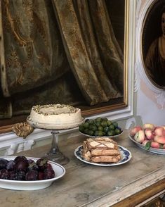 a table topped with plates of food next to a painting