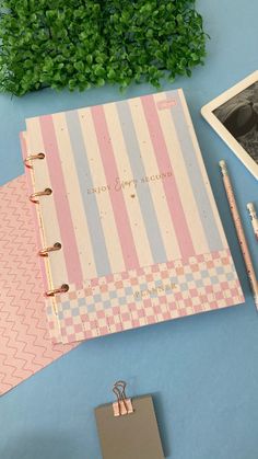 an open notebook sitting on top of a desk next to a pen and photo album