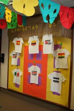 a bulletin board with t - shirts hanging from it's sides and flags on the wall