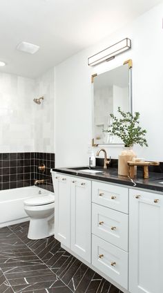 a bathroom with black and white tile flooring and gold accents on the vanity, toilet and bathtub