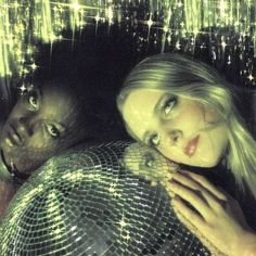 two people standing next to each other in front of a disco ball