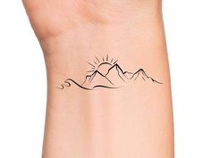 a small wrist tattoo with mountains on it