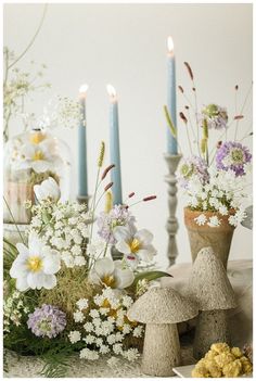 a table topped with vases filled with flowers and candles