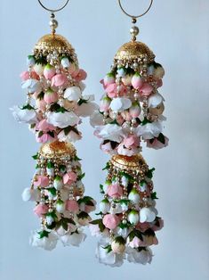 two pairs of pink and white flowers hanging from gold hoop earrings with pearls on them