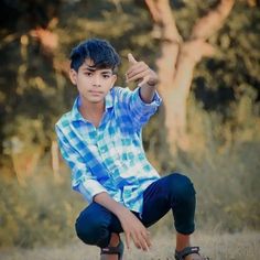 a young boy sitting on the ground giving a thumbs up