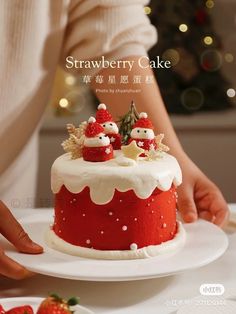 there is a red and white cake with santa clause decorations on the top, sitting on a plate next to strawberries