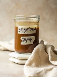 a glass jar filled with gingerbread syrup sitting on top of a white plate next to a napkin