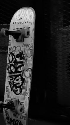 black and white photograph of a skateboard with graffitti on the bottom part