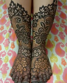 two feet with henna tattoos on them sitting on top of a flowery blanket