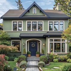 a green house with lots of windows and plants on the front lawn in front of it