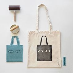 a tote bag with an eye drawn on it next to a rubber stamp and scissors