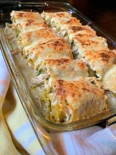 a casserole dish with cheese and vegetables in it sitting on a tablecloth