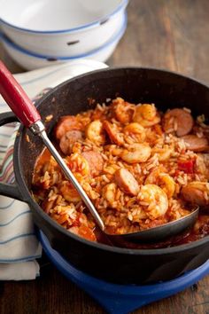 a skillet filled with shrimp and rice on top of a wooden table