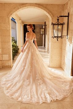 a woman in a wedding dress is walking through an archway with her back to the camera