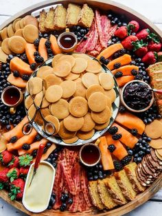 a platter filled with cookies, fruit and crackers on top of a table