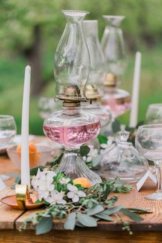 a wooden table topped with glass vases and candles