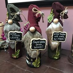 three wine bottle gnomes are sitting on a table with chalkboards attached to them