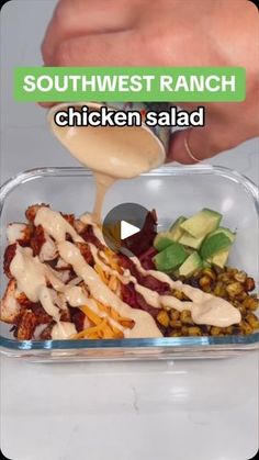 a person pouring ranch dressing over a chicken salad in a plastic container with other food items