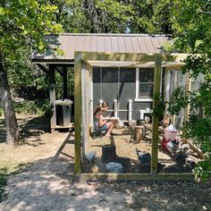 a woman sitting on the ground in front of a chicken coop with her chickens inside