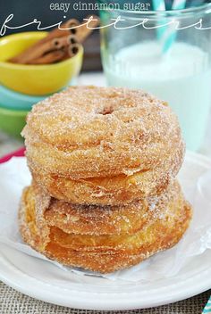 three cinnamon sugar donuts stacked on top of each other in front of a glass of milk