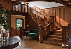 a living room with wood paneling and stairs next to a green couch in front of a window