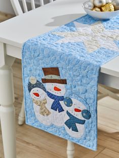 a snowman table runner on a white dining room table